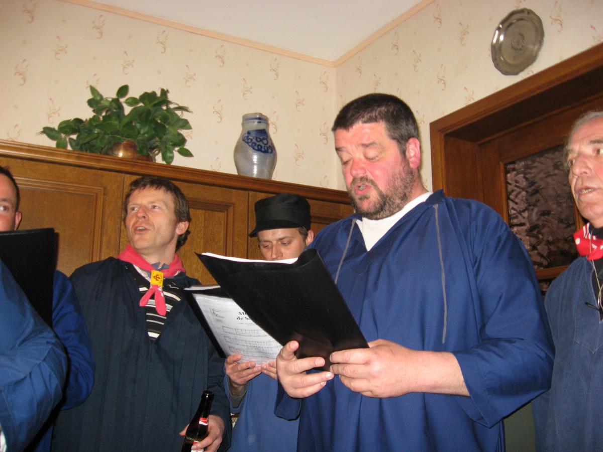 Chorale d’hommes habillés en costume traditionnel des Ardennais (sarreau, blouse bleue, casquette noire et foulard rouge).